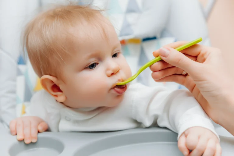 mother gives fruit sauce babymom feeds baby highchairbaby food scaled